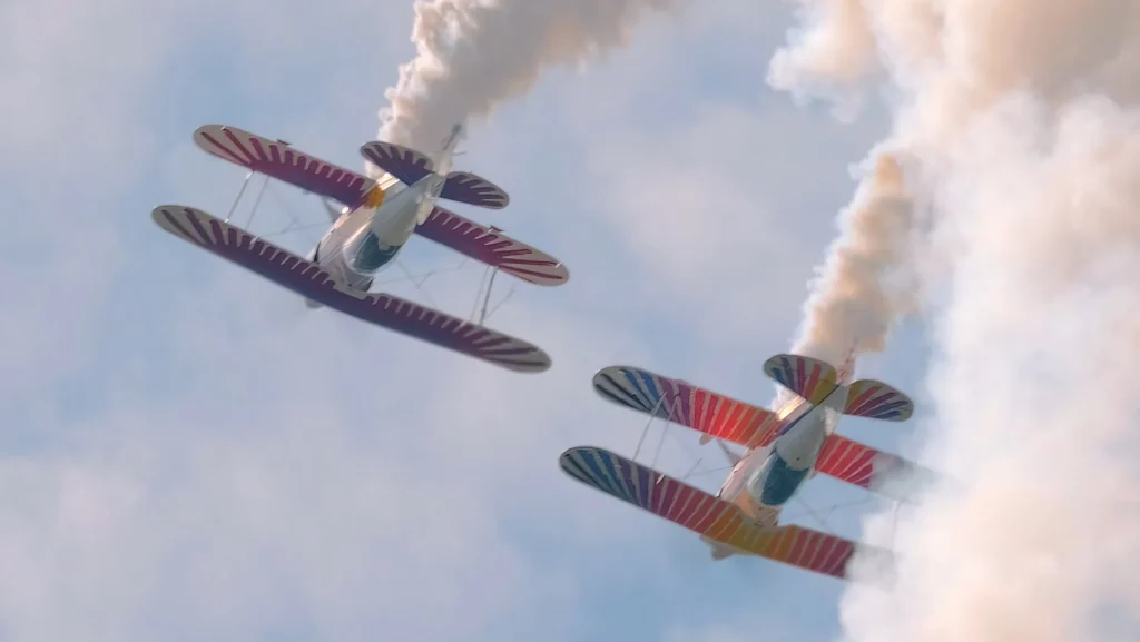 Two biplanes from NextGen Eagles perform aerobatics at the 2024 Lake Cumberland Air Show, leaving smoke trails.