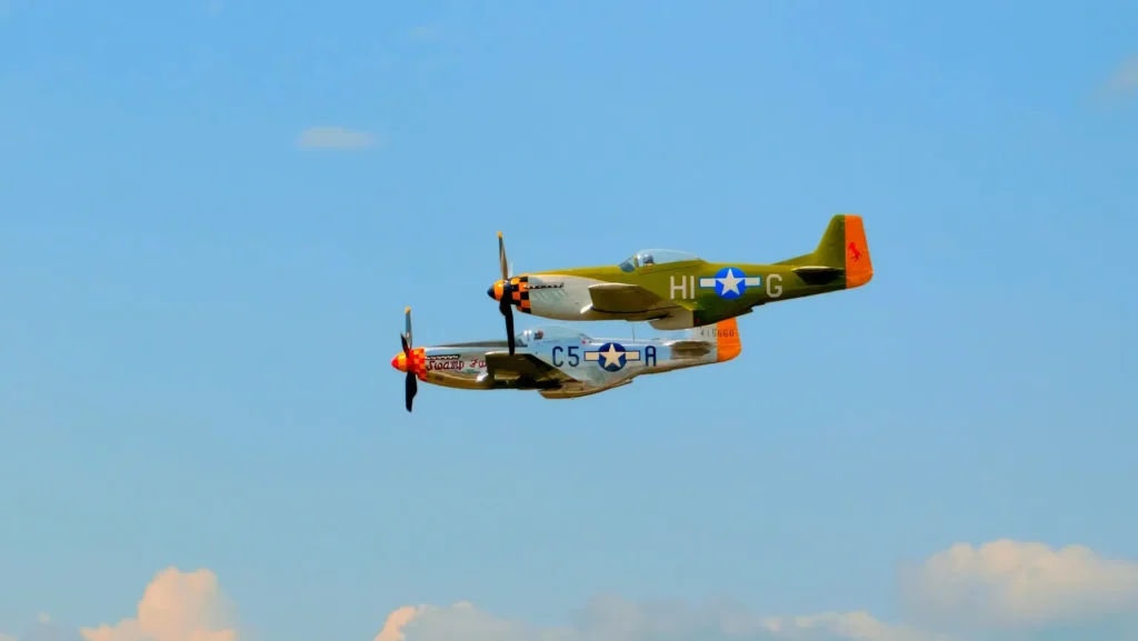 Two P-51 Mustangs flying at the 2024 Lake Cumberland Air Show in Kentucky under a clear sky.